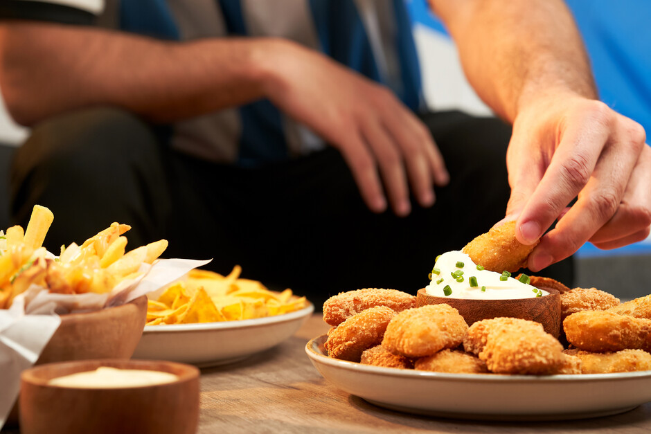 The image shows a man eating unhealthy foods