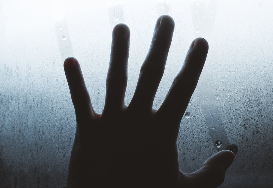 The image shows a hand on a window